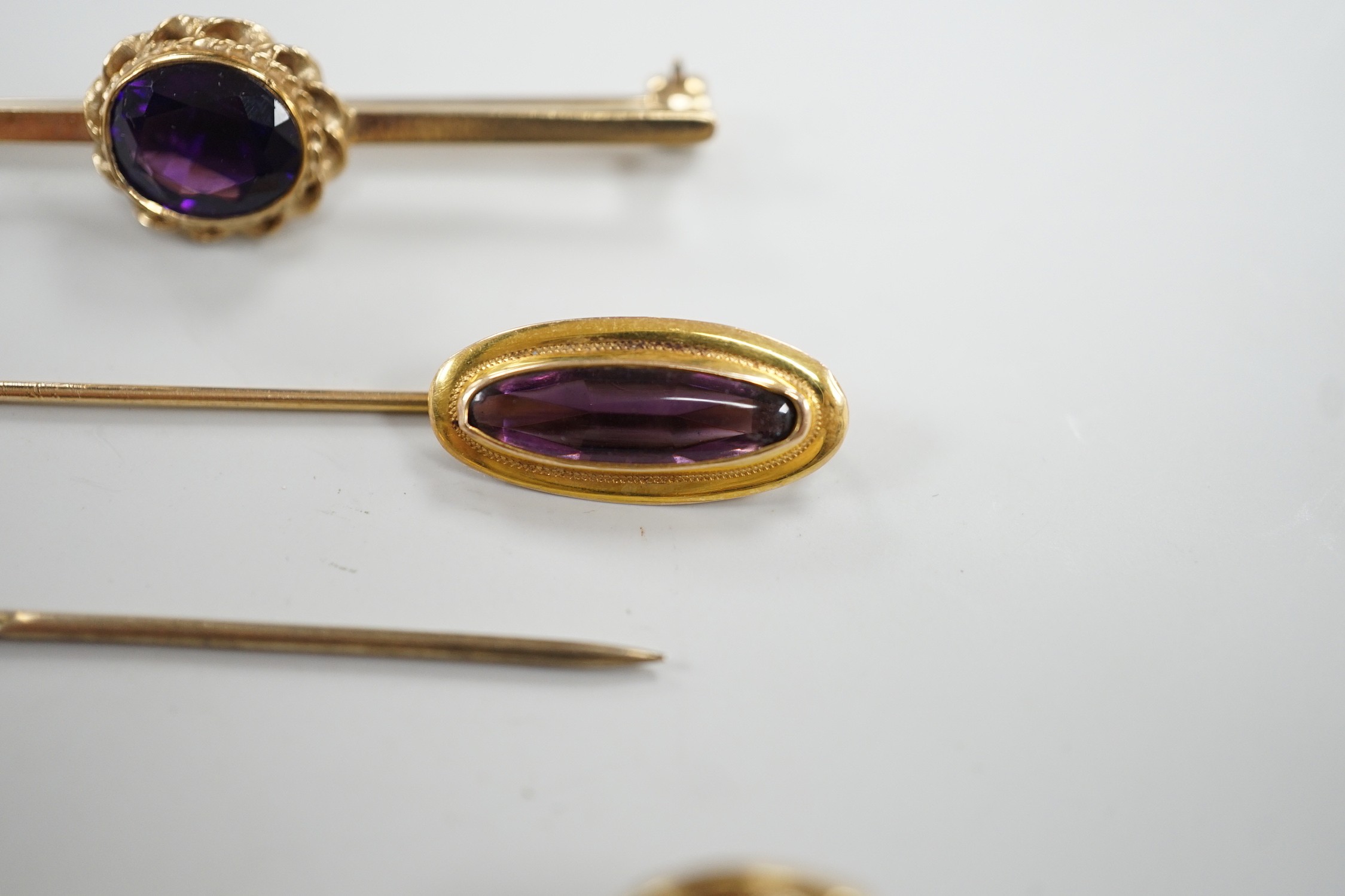 Three assorted yellow metal and gem set stick pins, including 9ct gold and diamond set horseshoe, 58mm and a modern 9ct gold and gem set bar brooch, gross weight 9.2 grams.